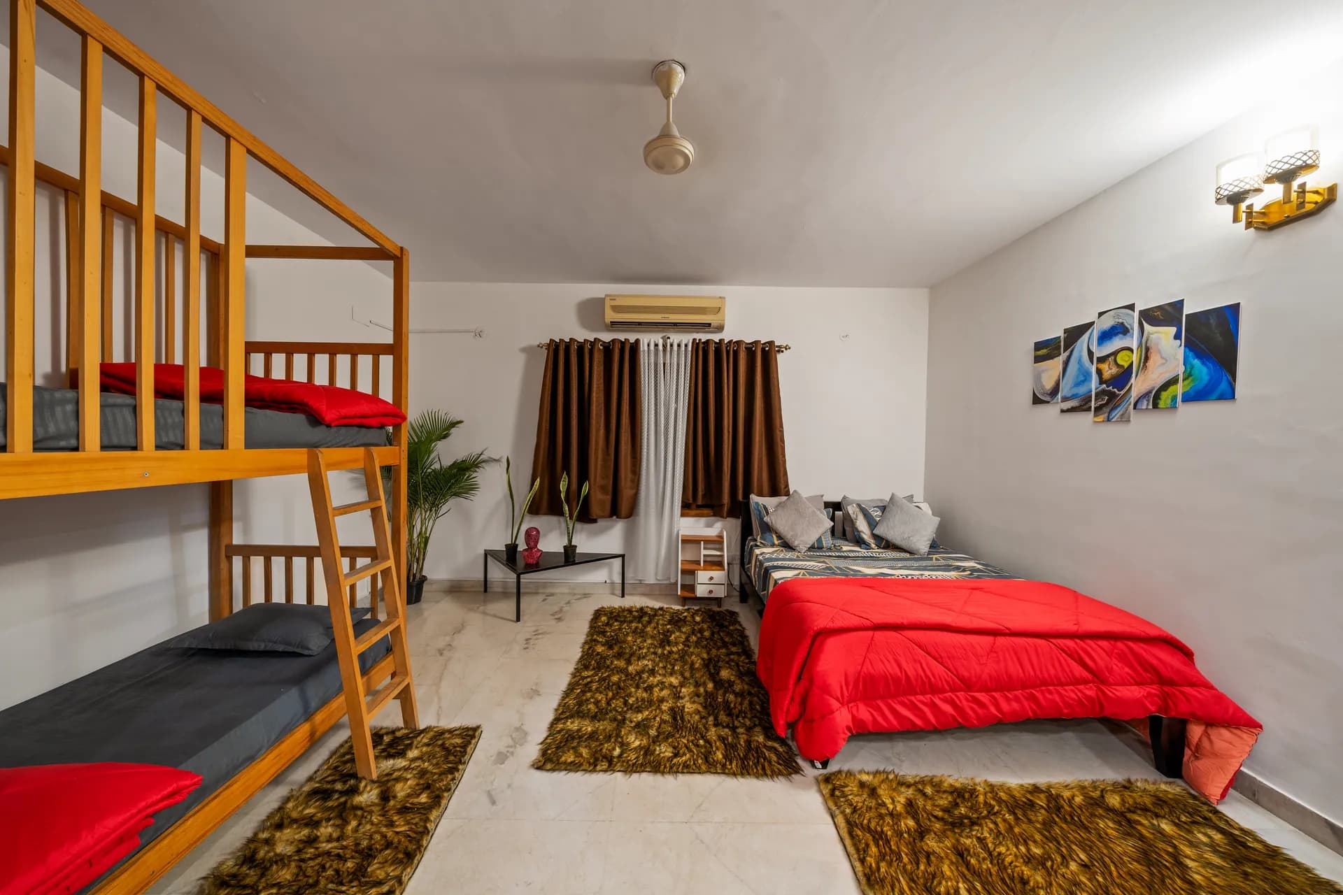 Bedroom with bunk beds, a double bed with red comforter, and fur rugs on marble floor.