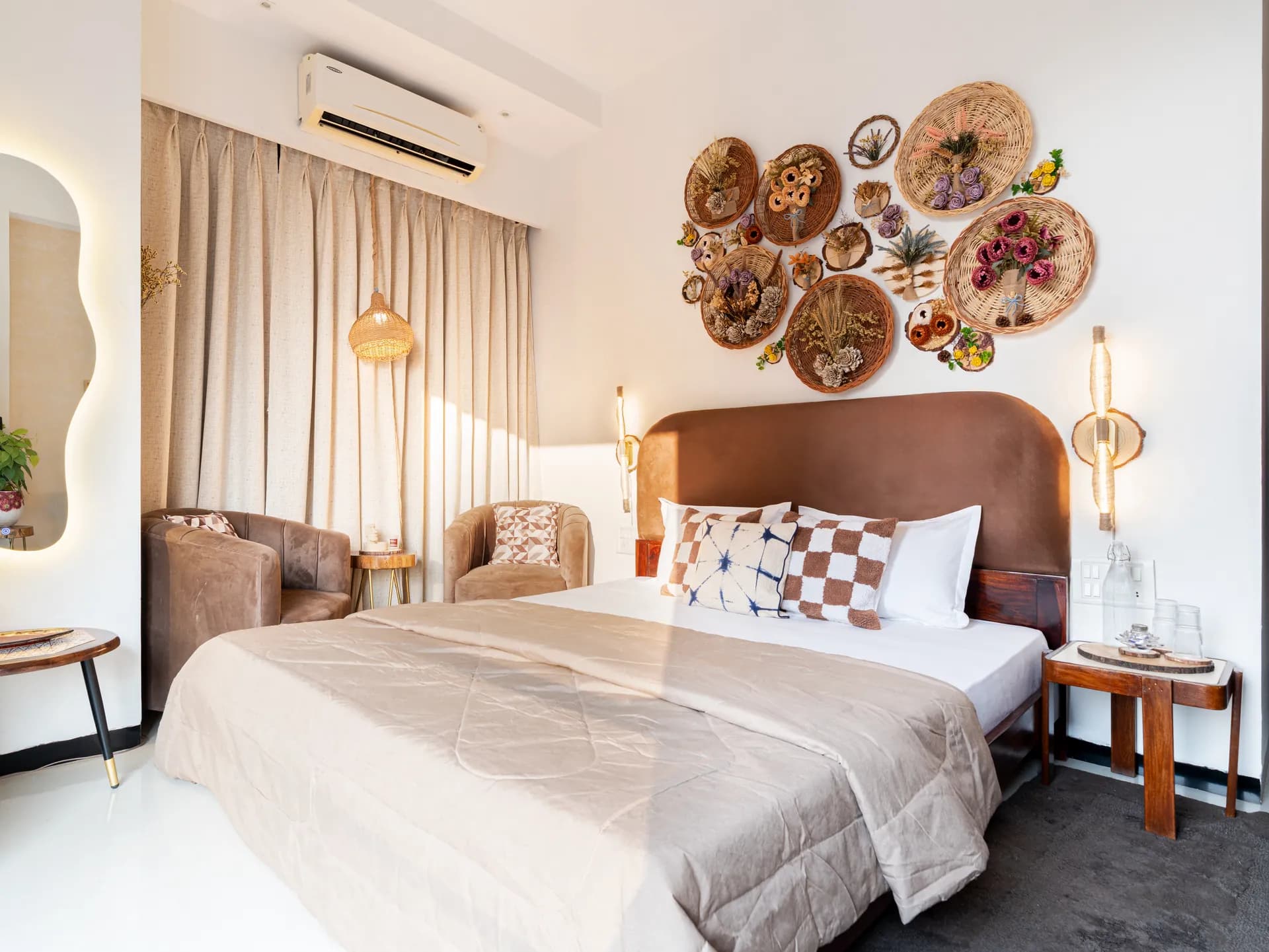 Bright bedroom with a king bed, wall of woven basket art, and a wall-mounted air conditioner above the curtains.