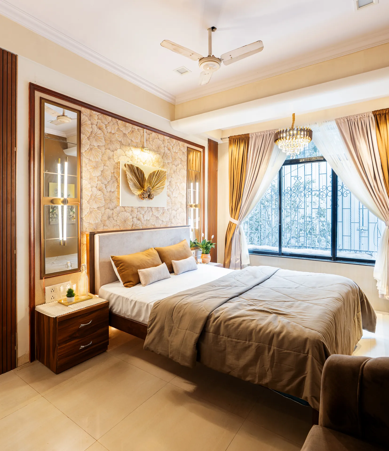Bedroom with a king bed, gold-accented curtains, and a bay window with decorative iron grille.