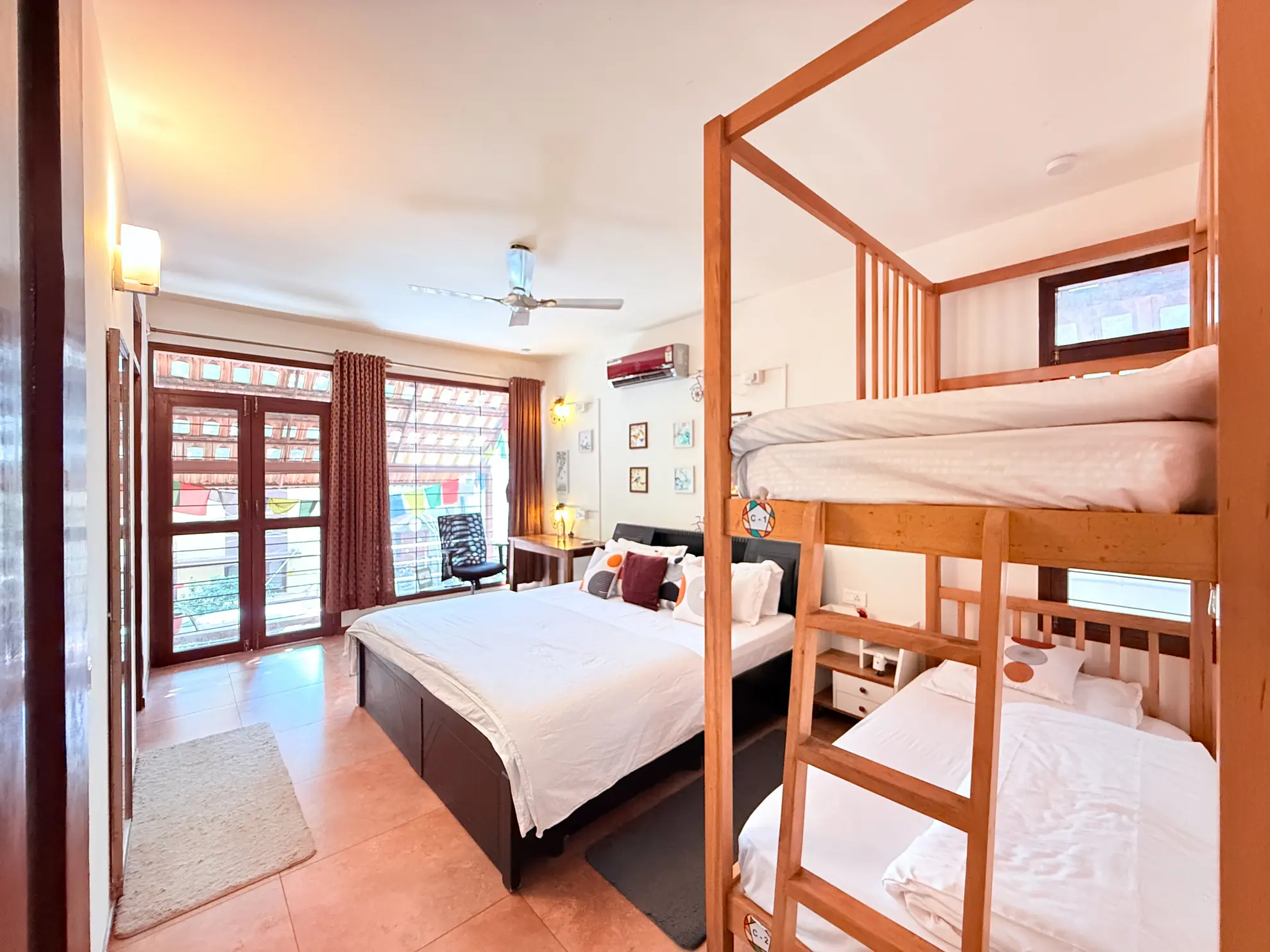 Bedroom with a double bed, bunk beds, ceiling fan and wall air conditioner, with glass doors to the outside.