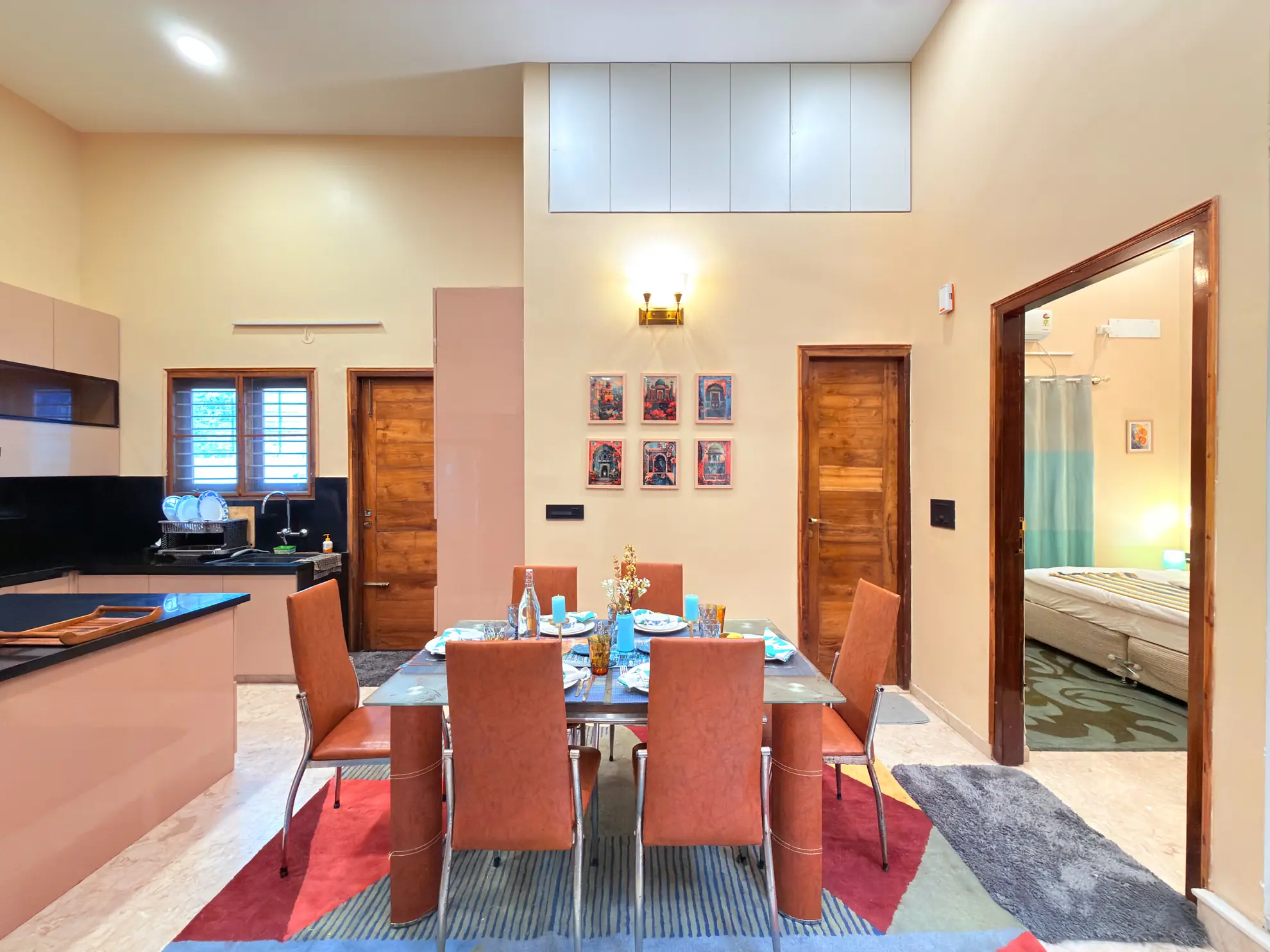 Dining area with glass table set for six, orange chairs, and an open view into a bedroom.