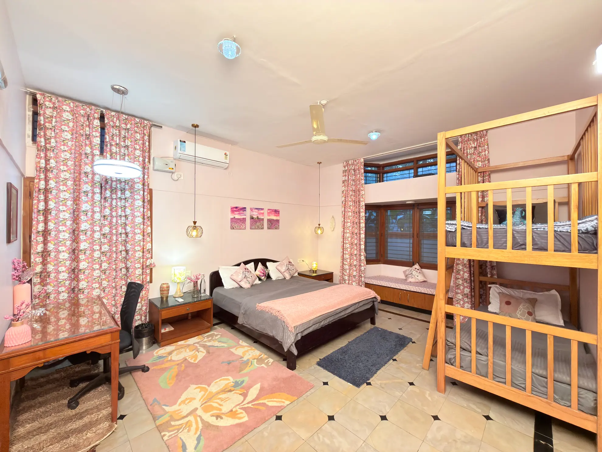 Bedroom with a double bed, bunk beds, a desk and a window seat under floral curtains.