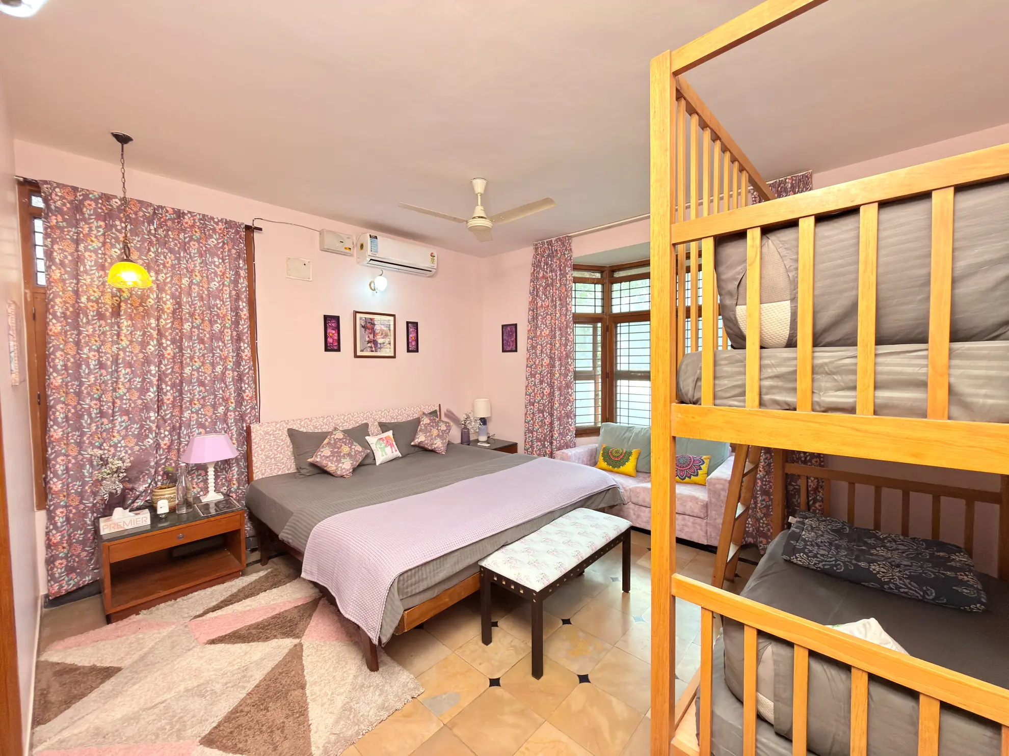 Bedroom with a double bed, bunk beds, and a pink-and-floral palette under a ceiling fan.