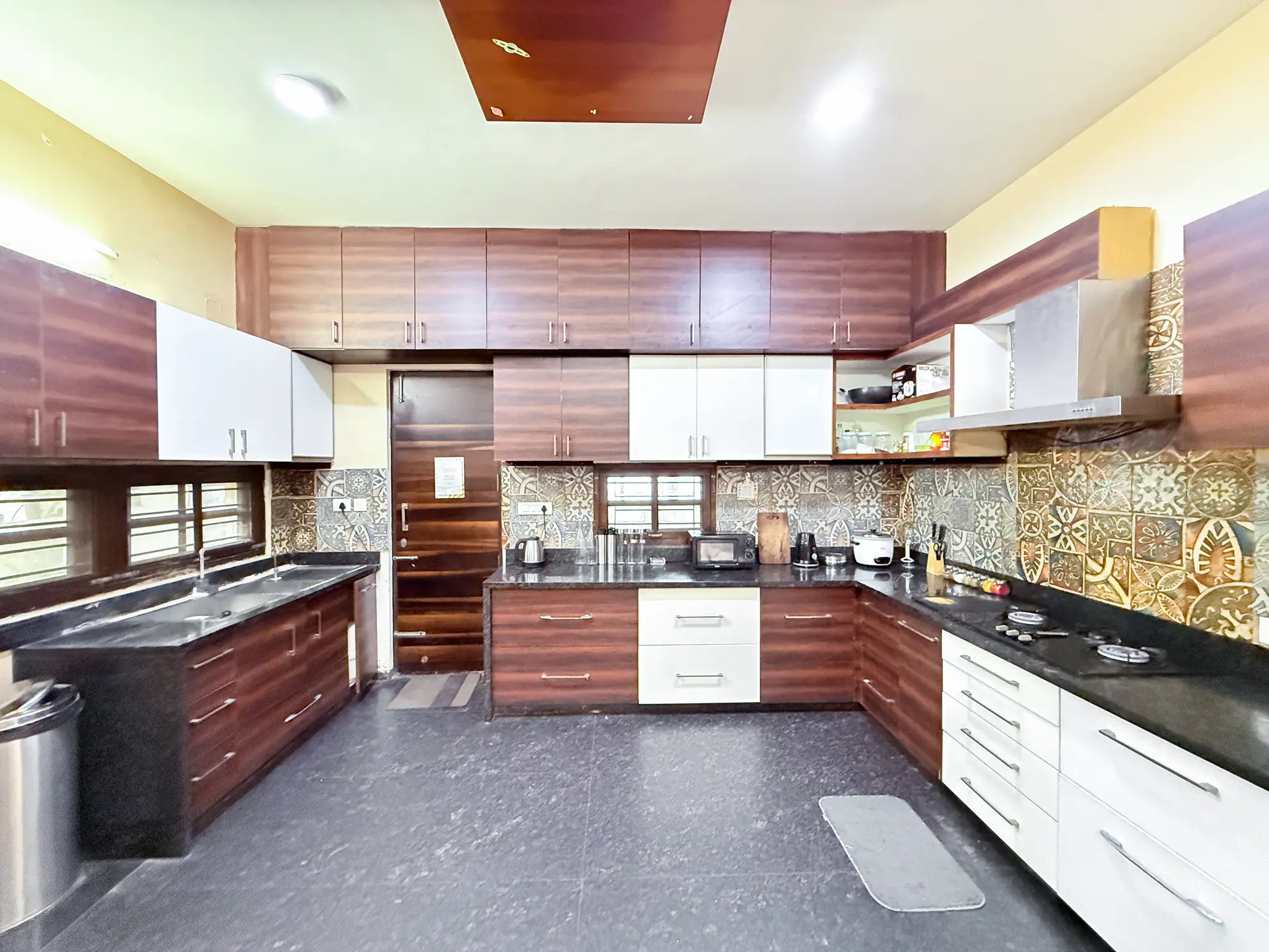 Galley-style kitchen with dark wood cabinets, black countertops, a gas hob and a microwave.