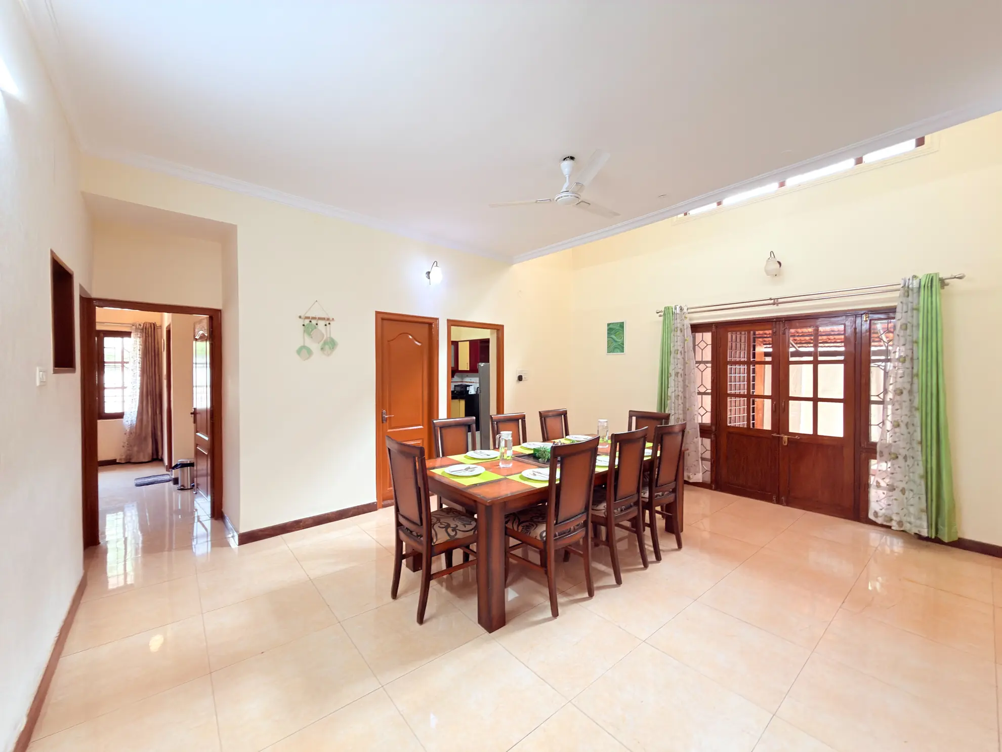 Dining room with a wooden table for eight, tiled floor, ceiling fan, and glass doors to the outside.